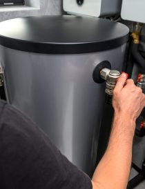 Modern electric boiler room in the house. Equipment for water heating system with automatic control unit. Close-up of a man's hand
